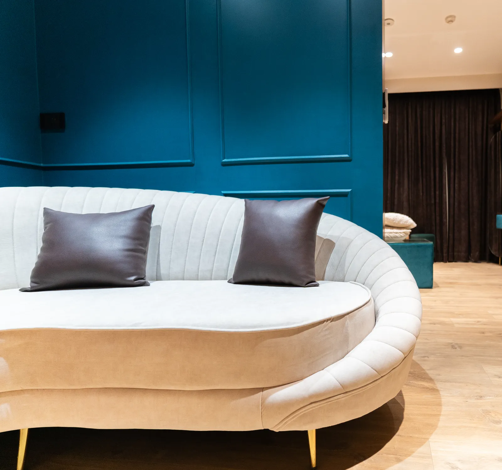Curved cream sofa against a teal panelled wall — Abhishek's Residence